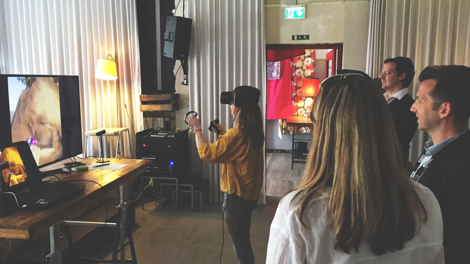 Frau mit VR-Brille an der Entertainment-Station, dahinter ein 50-Zoll-Screen